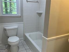 bathroom featuring tile patterned floors, toilet, and tiled shower / bath combo