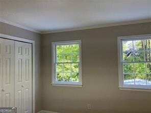 unfurnished bedroom with crown molding and a closet