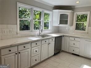 kitchen with white cabinetry, decorative backsplash, dishwasher, and light stone countertops