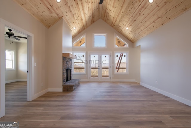 unfurnished living room with wood ceiling, light hardwood / wood-style flooring, a wealth of natural light, ceiling fan, and a fireplace