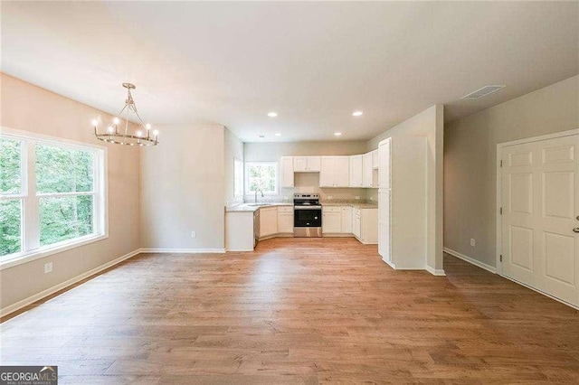 kitchen with pendant lighting, white cabinetry, a chandelier, light wood-type flooring, and electric stove