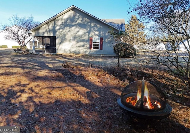 view of property exterior featuring an outdoor fire pit and a sunroom