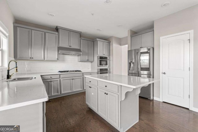 kitchen featuring dark hardwood / wood-style flooring, sink, stainless steel appliances, and a center island