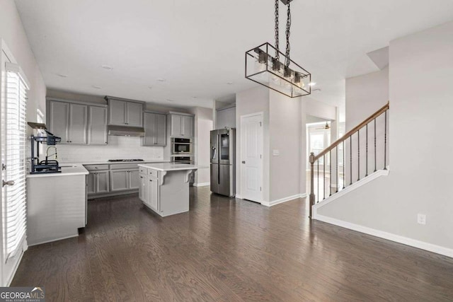 kitchen featuring a center island, gray cabinets, pendant lighting, stainless steel appliances, and backsplash