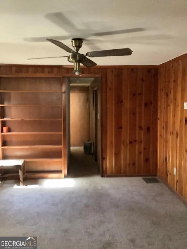 interior space with ceiling fan and wooden walls