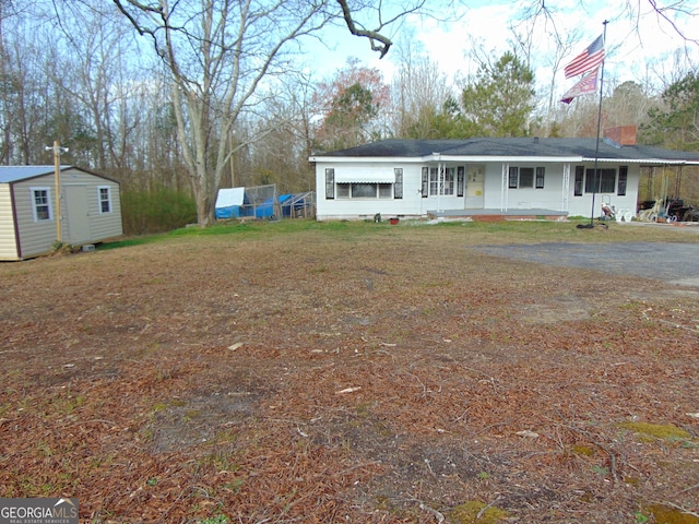 view of front of house featuring an outbuilding, covered porch, a storage shed, and a front yard