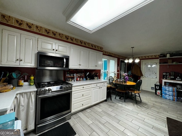 kitchen with pendant lighting, stainless steel appliances, crown molding, and white cabinets