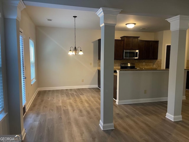 kitchen with decorative columns, wood-type flooring, and dark brown cabinets