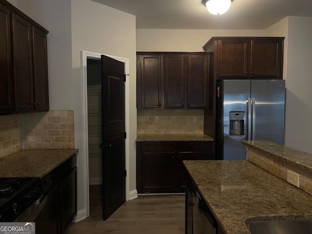 kitchen featuring dark stone countertops, stainless steel fridge, dark hardwood / wood-style flooring, and decorative backsplash