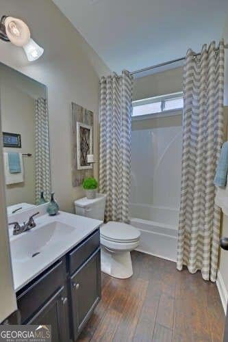 full bathroom with lofted ceiling, hardwood / wood-style flooring, vanity, toilet, and shower / bath combo with shower curtain