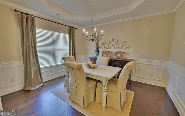 dining area with a chandelier, dark hardwood / wood-style flooring, a raised ceiling, and crown molding