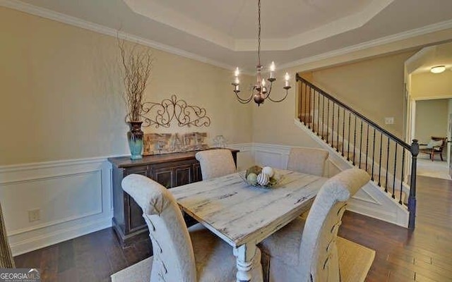 dining room with a raised ceiling, crown molding, an inviting chandelier, and dark hardwood / wood-style flooring