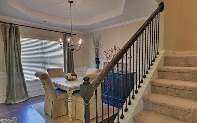 dining area with hardwood / wood-style flooring, crown molding, and a raised ceiling