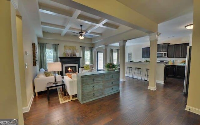 living room featuring ornate columns, beamed ceiling, dark hardwood / wood-style flooring, coffered ceiling, and ceiling fan