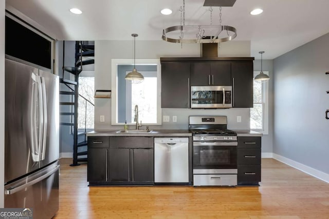 kitchen featuring pendant lighting, stainless steel appliances, sink, and light hardwood / wood-style flooring