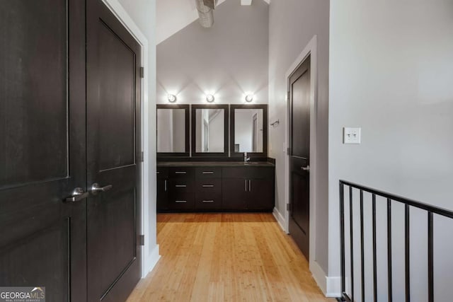 bathroom with hardwood / wood-style flooring, vanity, and vaulted ceiling