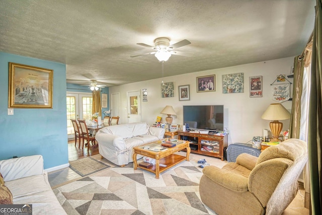 living room with ceiling fan, french doors, and a textured ceiling