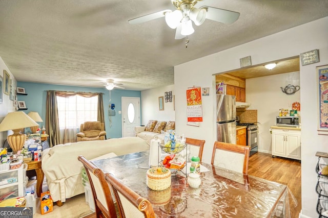 dining area with ceiling fan, light hardwood / wood-style floors, and a textured ceiling