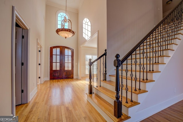 foyer entrance with crown molding, plenty of natural light, light hardwood / wood-style flooring, and a high ceiling