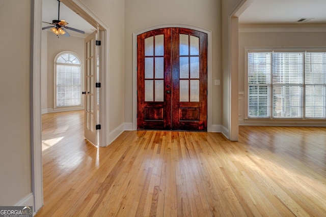 entrance foyer with french doors, ceiling fan, ornamental molding, and light wood-type flooring