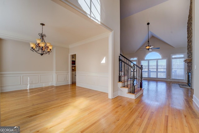 foyer entrance with crown molding, hardwood / wood-style flooring, a fireplace, ceiling fan with notable chandelier, and vaulted ceiling