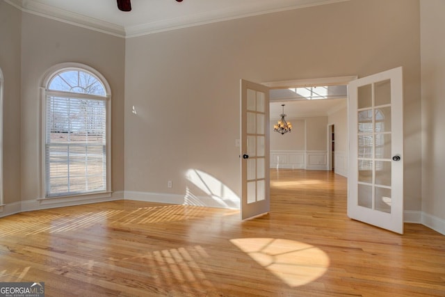 spare room featuring ornamental molding, ceiling fan with notable chandelier, and french doors