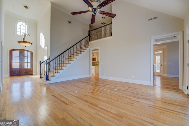 unfurnished living room featuring a towering ceiling, french doors, and a healthy amount of sunlight