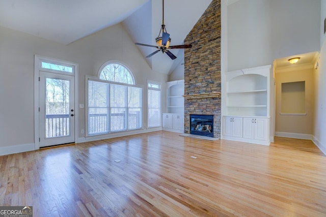 unfurnished living room featuring a stone fireplace, built in features, high vaulted ceiling, ceiling fan, and light hardwood / wood-style flooring