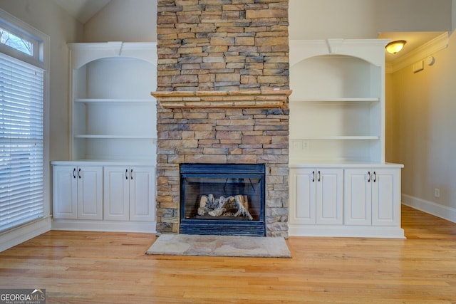 unfurnished living room featuring a fireplace, built in features, and light hardwood / wood-style flooring