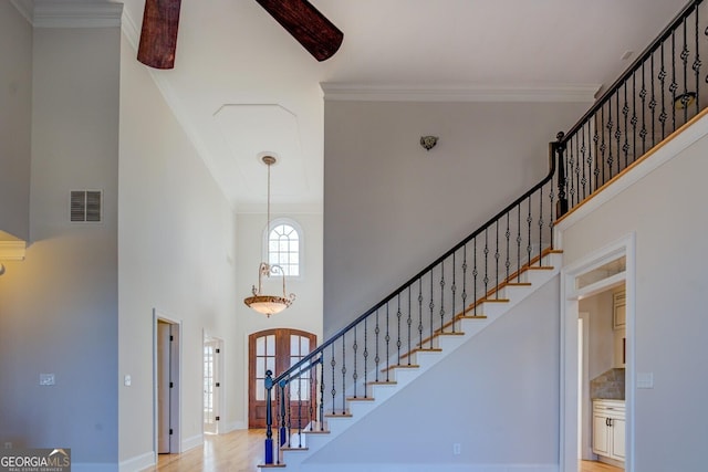 foyer with light hardwood / wood-style flooring, ornamental molding, and a high ceiling