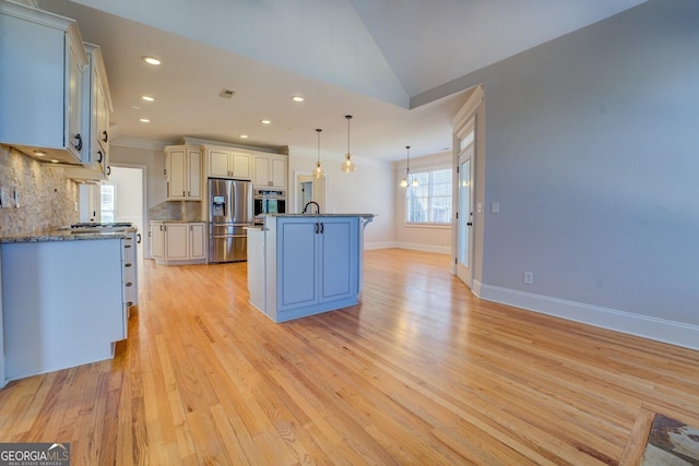 kitchen featuring a center island, light hardwood / wood-style flooring, appliances with stainless steel finishes, pendant lighting, and backsplash