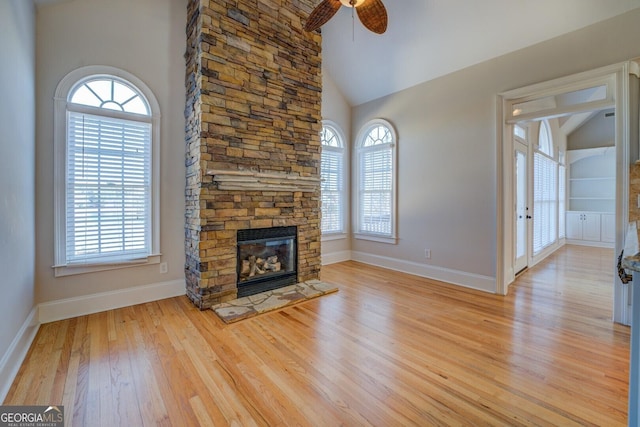 unfurnished living room featuring ceiling fan, high vaulted ceiling, a fireplace, and light hardwood / wood-style floors