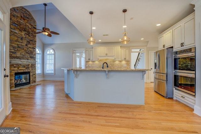 kitchen featuring a breakfast bar, appliances with stainless steel finishes, backsplash, hanging light fixtures, and white cabinets