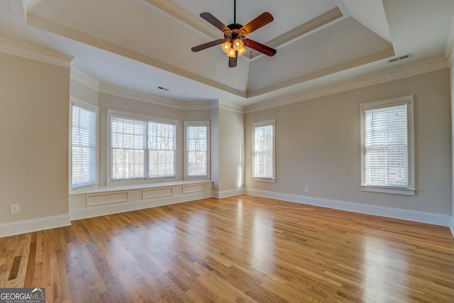 unfurnished room featuring light hardwood / wood-style flooring, ornamental molding, a raised ceiling, and ceiling fan