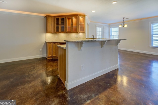 kitchen with a breakfast bar, hanging light fixtures, ornamental molding, kitchen peninsula, and light stone countertops