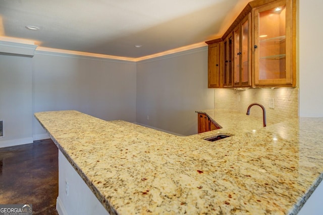 kitchen with light stone counters, kitchen peninsula, and sink