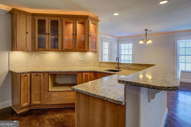 kitchen with light stone counters, a healthy amount of sunlight, decorative light fixtures, and sink