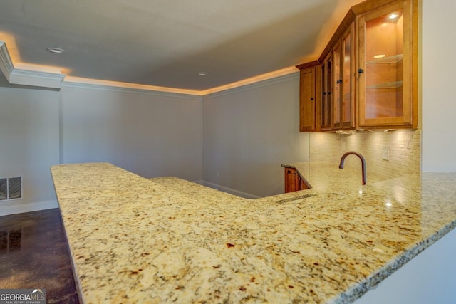 kitchen featuring ornamental molding, light stone counters, and kitchen peninsula