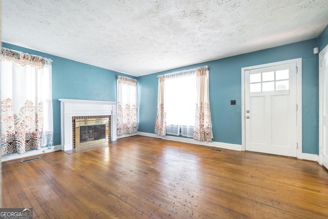 unfurnished living room featuring wood-type flooring, a textured ceiling, and a fireplace