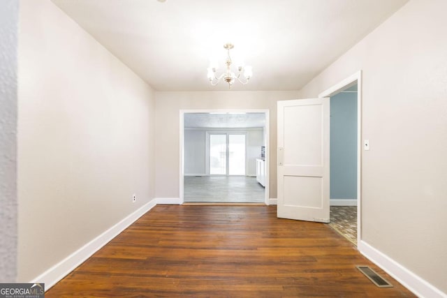 unfurnished dining area featuring dark wood-type flooring and a chandelier