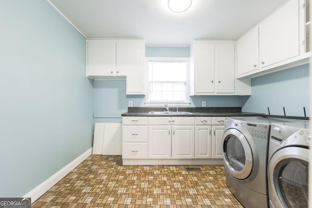 clothes washing area featuring cabinets, sink, and washer and clothes dryer