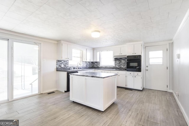 kitchen featuring tasteful backsplash, white cabinets, a center island, and black appliances