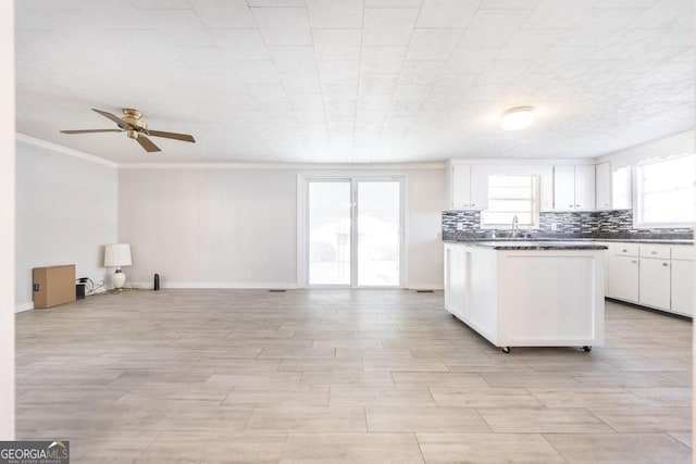 kitchen featuring sink, white cabinets, backsplash, ornamental molding, and ceiling fan