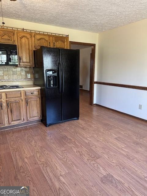 kitchen with tasteful backsplash, wood-type flooring, a textured ceiling, and black appliances