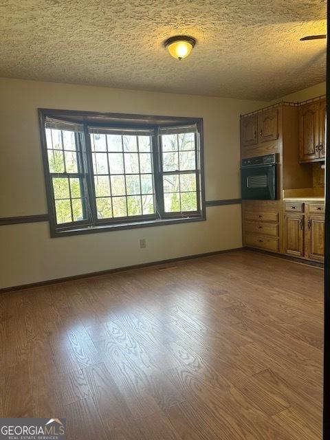 interior space with oven, a textured ceiling, and light wood-type flooring