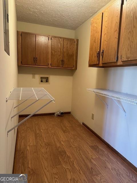 laundry room featuring cabinet space, a textured ceiling, wood finished floors, and hookup for a washing machine