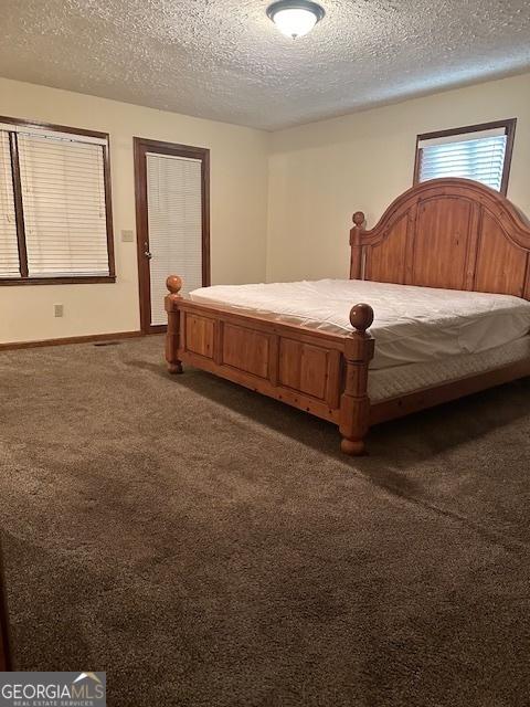 bedroom featuring dark carpet and a textured ceiling