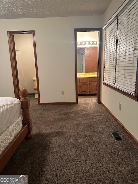 unfurnished bedroom featuring carpet flooring, connected bathroom, and a textured ceiling