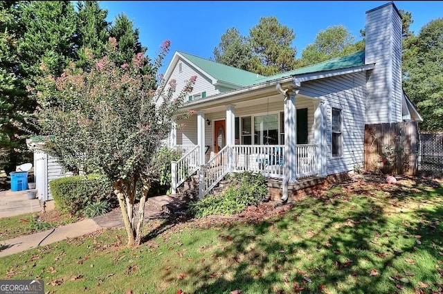 view of front facade featuring a chimney, fence, a porch, and a front yard