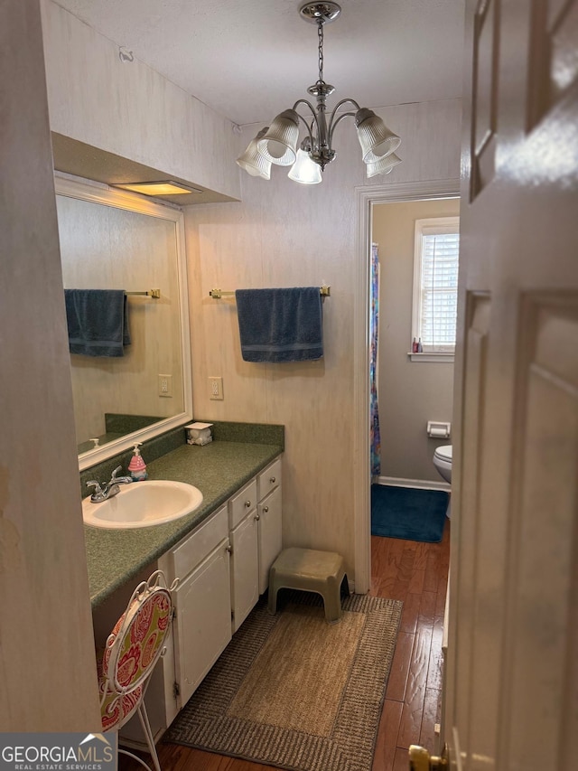 bathroom featuring vanity, hardwood / wood-style flooring, toilet, and an inviting chandelier